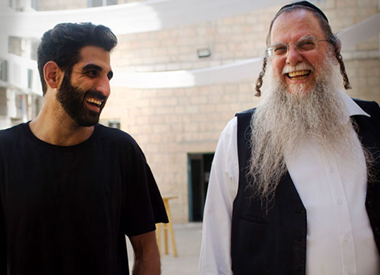 Two men smiling and talking while walking outdoors