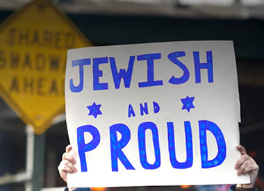 Person holding a sign that reads ‘Jewish and Proud’