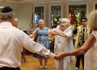 Older woman smiling and dancing with other people